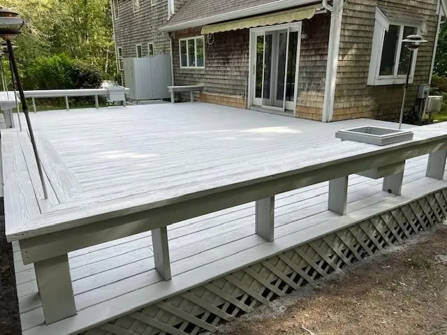 Large gray composite deck with a built-in bench and lattice skirting