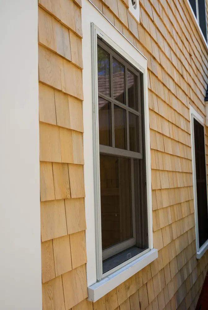 New natural cedar shingle siding with straight courses around a white window